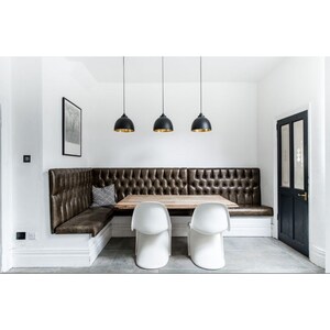 A stylish dining nook featuring a tufted leather banquette, rustic wooden table, sleek white chairs,
